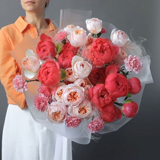 There's a woman holding a gorgeous, inexpensive bouquet of red peonies and Juliet roses.